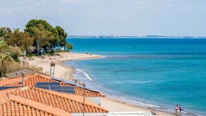 Küstensicht mit Strand, blauem Himmel und Solaranlage auf einem Gebäude.