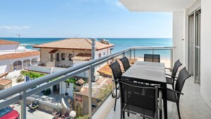 Ein Balkon mit Tisch und Stühlen mit Blick auf einen Strand.