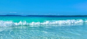 A clear view of turquoise ocean water with waves breaking on the shore.