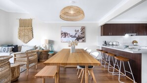 A modern kitchen with dark wooden cabinets, a white countertop, and a hanging woven light fixture. - Meira Haus - Belle Escapes Jervis Bay (Sanctuary Point)