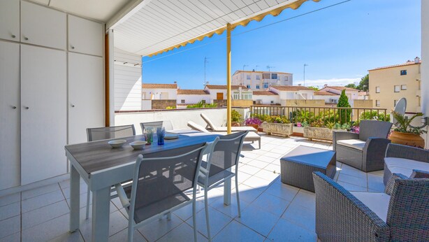 A balcony with a dining table and chairs, a sofa, and potted plants.