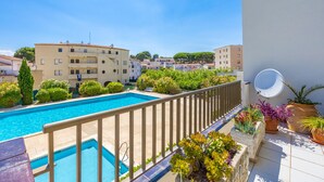 A rooftop pool with a view of surrounding buildings, a satellite dish, and potted plants.