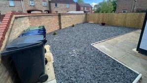 A backyard with a gravel surface, a brick wall, and a wooden fence. - Remarkable Studio flat in Cambridge (Cambridge)