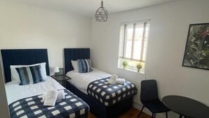 Une chambre d’hôtel avec deux lits, une petite table, une chaise et une fenêtre donnant sur un beau paysage.