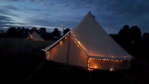 Une tente avec un toit conique et des guirlandes lumineuses le long des bords.