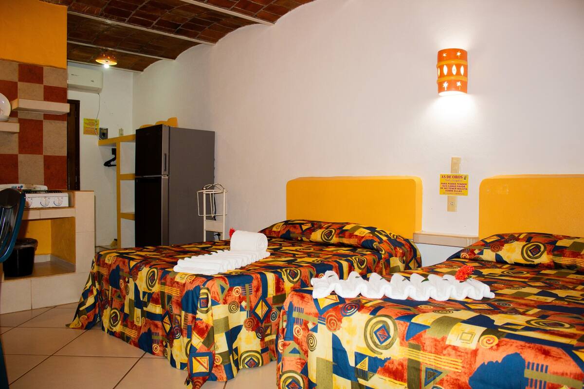 Une chambre d’hôtel avec deux lits, un réfrigérateur, un lavabo et un miroir.