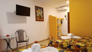 Habitación de hotel con dos camas, un escritorio, una silla, un televisor y un equipo de aire acondicionado.