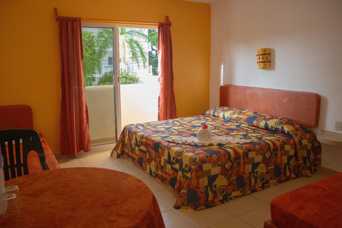Une chambre avec un lit, une chaise, une table et une porte coulissante donnant sur un balcon.