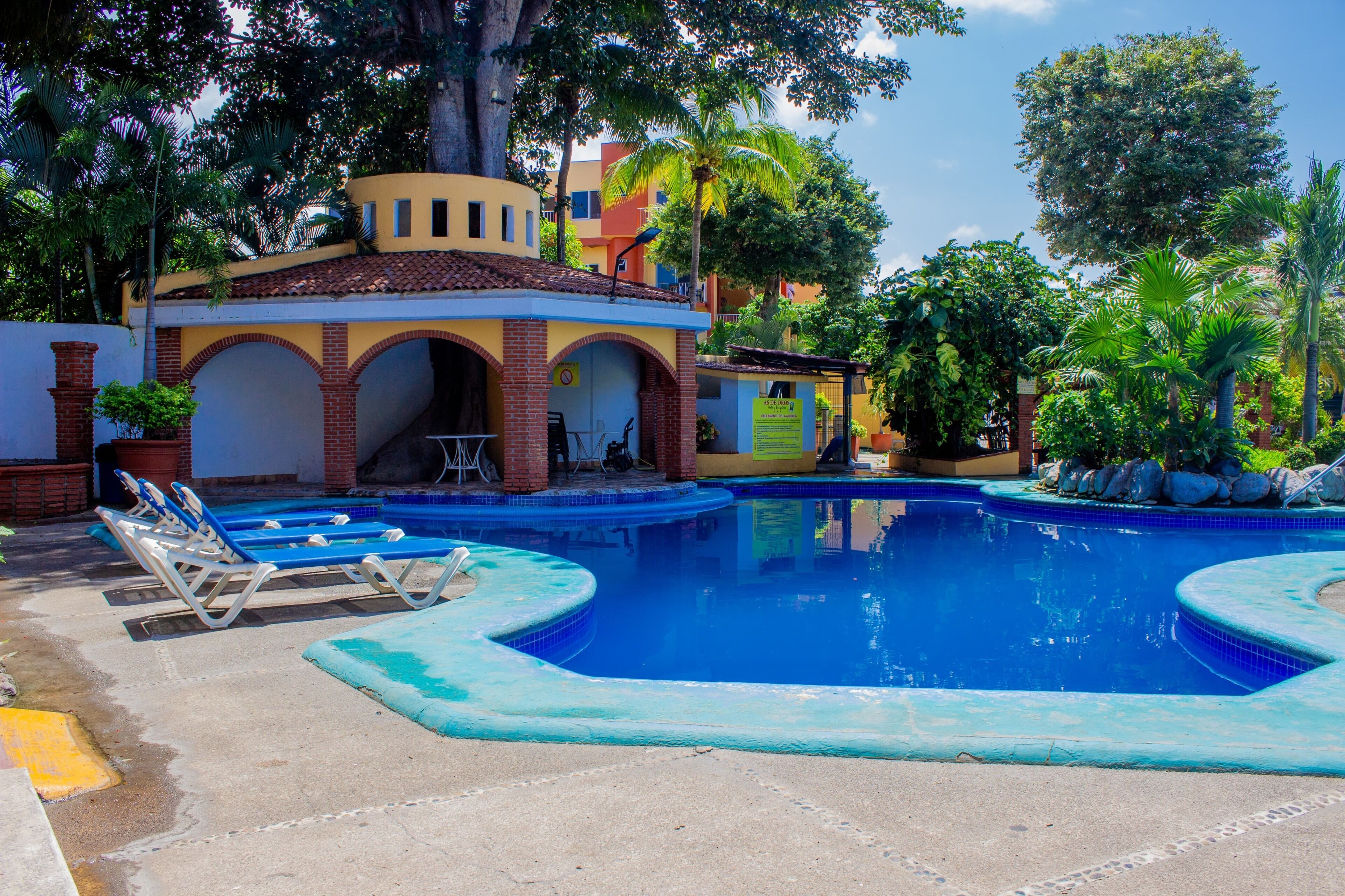 A swimming pool with lounge chairs and a small building with arches.