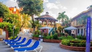 Un patio de resort con sillas de descanso, un pabellón y una zona de piscina.