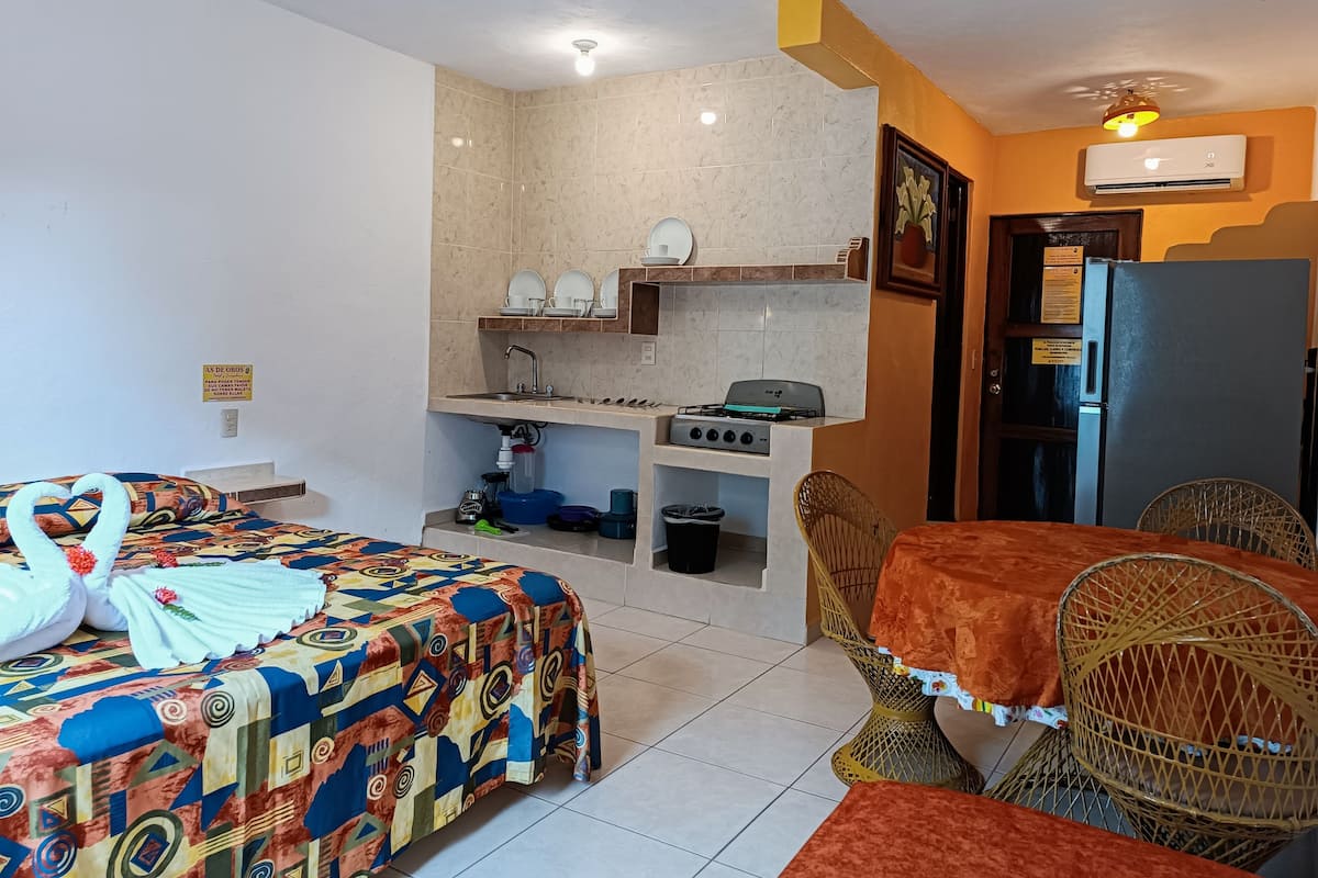 Une chambre d’hôtel compacte comprenant un lit, une petite kitchenette, un coin repas et une salle de bain.