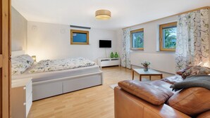 Une chambre moderne équipée d’un lit, d’un canapé, d’une petite table et d’un téléviseur.