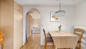 Une cuisine moderne avec des meubles de rangement en bois, une table à manger avec des chaises et un luminaire suspendu.
