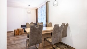 A dining area with a wooden table, six chairs, and two pendant lights. - Holiday Apartment "Goodlife Top 1" with Mountain View & Wi-Fi (Saalbach)