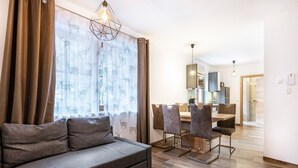 A modern living room with a sofa, dining area, and kitchen in the background. - Holiday Apartment "Goodlife Top 1" with Mountain View & Wi-Fi (Saalbach)