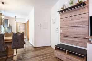 A modern interior with a wooden floor, a bench, a wall-mounted shelf with decorative items, and a door with a light switch. - Holiday Apartment "Goodlife Top 1" with Mountain View & Wi-Fi (Saalbach)