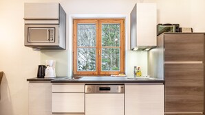 A modern kitchen with a built-in microwave, a dishwasher, and a window with a view of trees. - Holiday Apartment "Goodlife Top 1" with Mountain View & Wi-Fi (Saalbach)