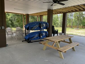 A covered patio area with a picnic table and two kayaks.