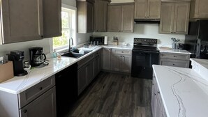 A modern kitchen with dark wood cabinets, a white countertop, and a central island. - New riverfront home across from Rock Bluff Springs on the Suwannee river (Branford)