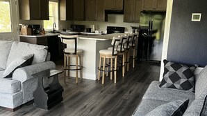 A modern kitchen with wooden cabinets, a central island with bar stools, and a built-in refrigerator. - New riverfront home across from Rock Bluff Springs on the Suwannee river (Branford)