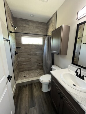 A bathroom with a shower, toilet, and sink.