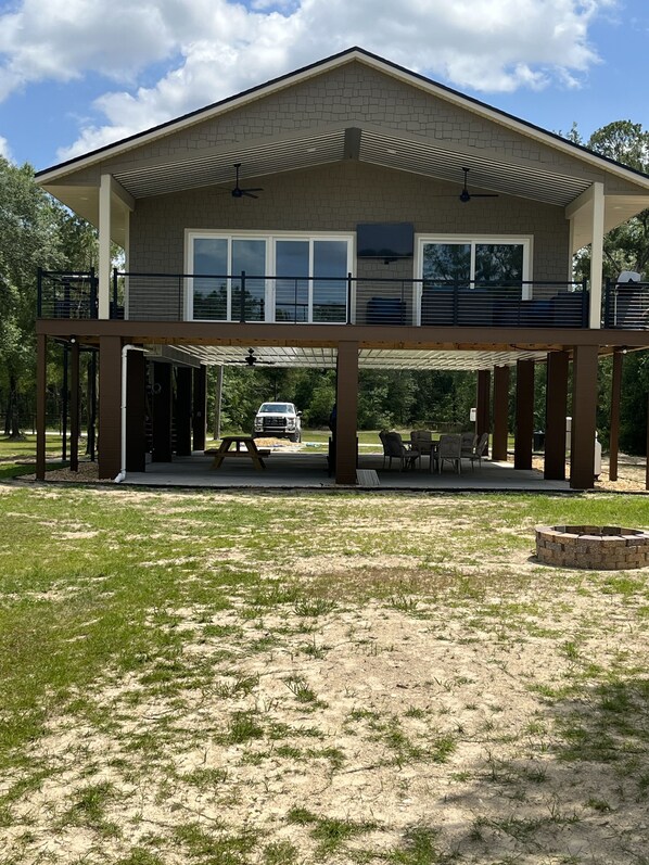A two-story house with a covered patio and a fire pit.
