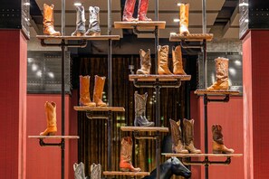 Une exposition de différentes sortes de bottes, suspendues à des étagères métalliques.