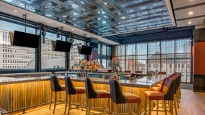 Eine moderne Bar mit Glasdecke, mehreren Bildschirmen und Blick auf die Stadtlandschaft.