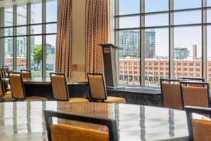 Une salle de conférence dotée de grandes fenêtres, d’un pupitre et offrant une vue sur le paysage urbain.
