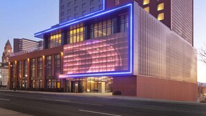 Een hotel met een opvallend 'CAMBRIA' bord, een moderne glazen gevel en een klassiek pand ernaast.