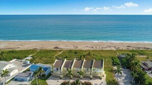 Una propiedad frente a la playa con varios edificios, una playa de arena y una vista despejada del océano.