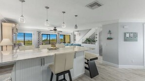 Una cocina moderna con una isla grande, iluminación colgante y vistas al exterior.