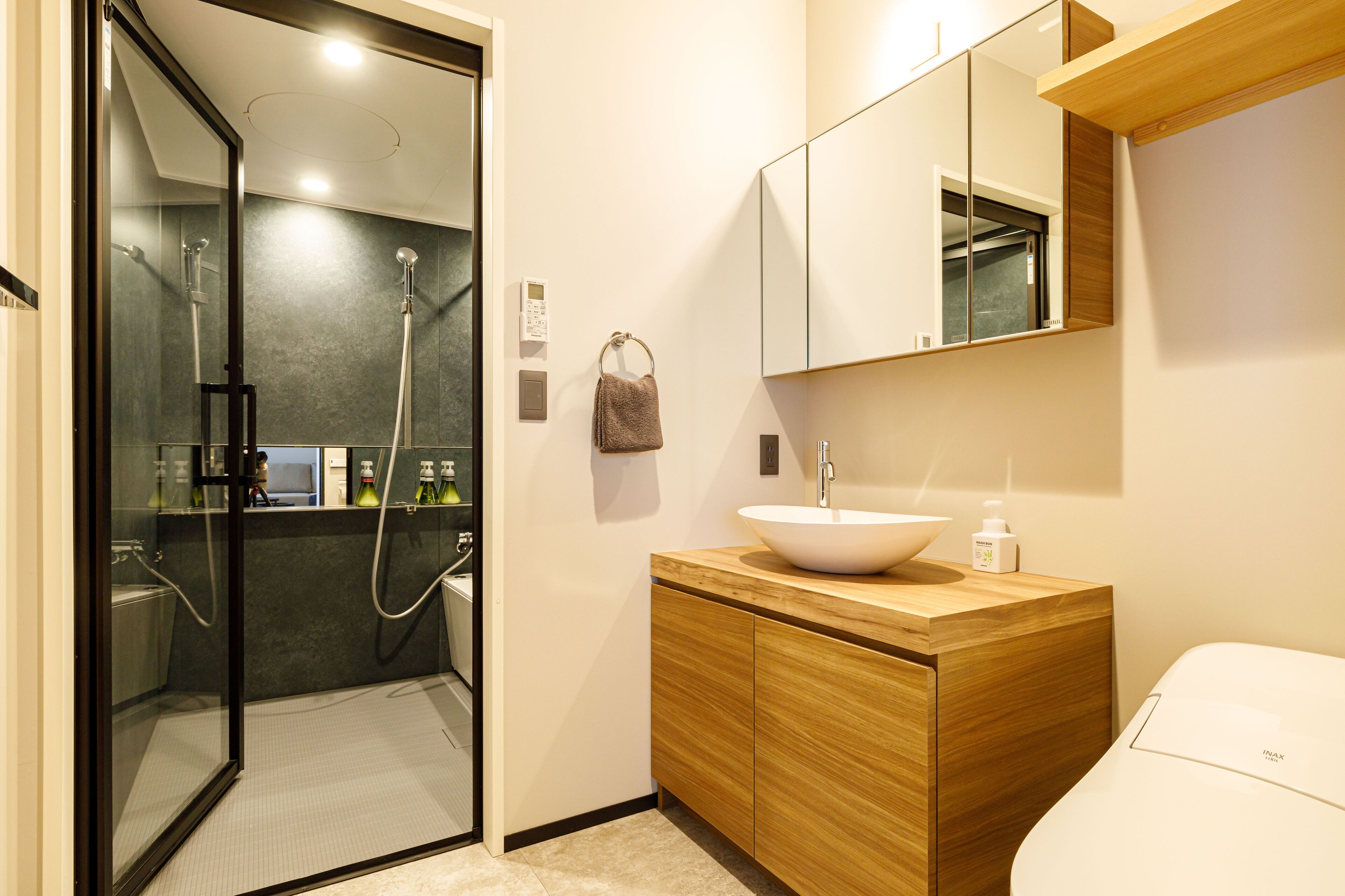 A modern bathroom with a glass-enclosed shower, a wooden vanity with a white sink, and a large mirror above the vanity.