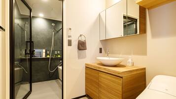 A modern bathroom with a glass-enclosed shower, a wooden vanity with a white sink, and a large mirror above the vanity.
