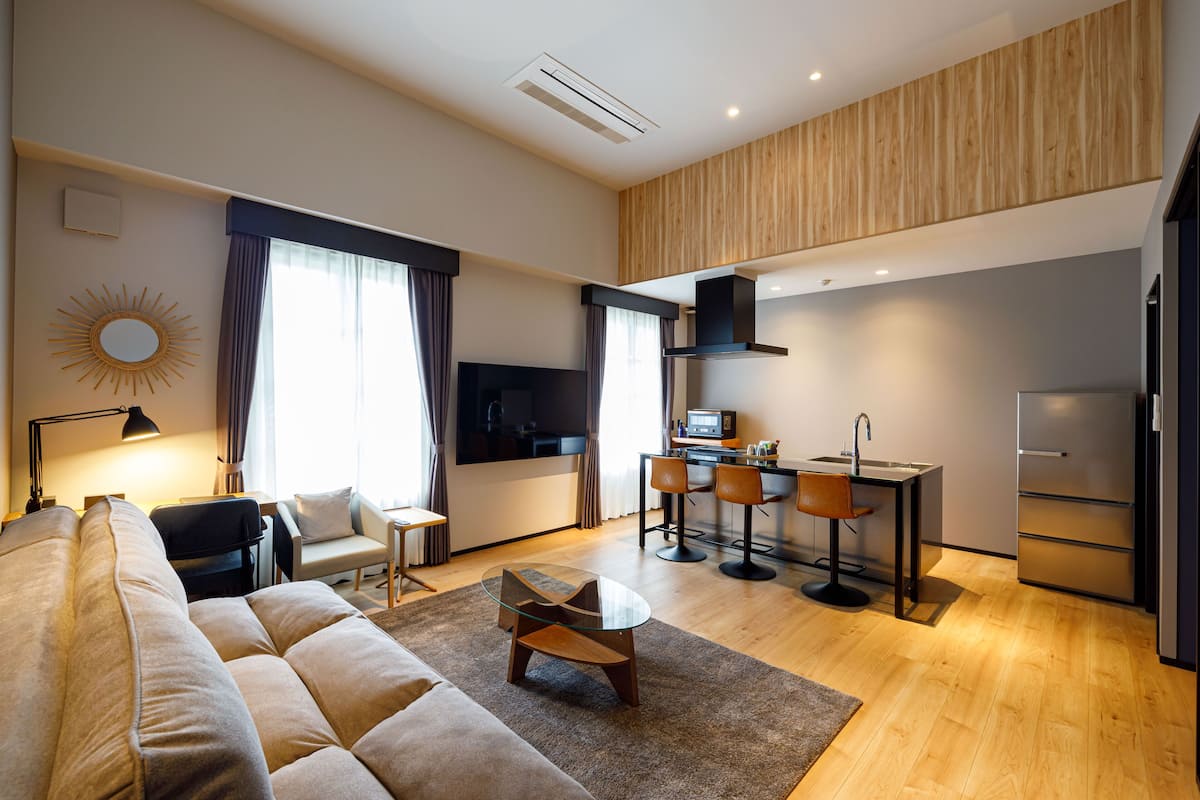 Un salon moderne avec un canapé, une table basse en verre et un coin repas comprenant des chaises et une petite table.