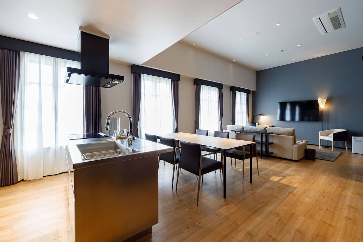 Une cuisine moderne dotée d’un îlot central, d’un coin repas avec des chaises, d’un canapé et d’un téléviseur à écran plat.