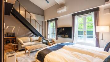 A modern bedroom with a bed, a sofa, a desk, and a staircase.