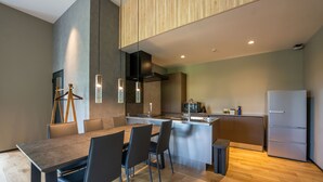 A modern kitchen with a dining area, wooden flooring, and a built-in refrigerator. - eau sol vert karuizawa club (Karuizawa)