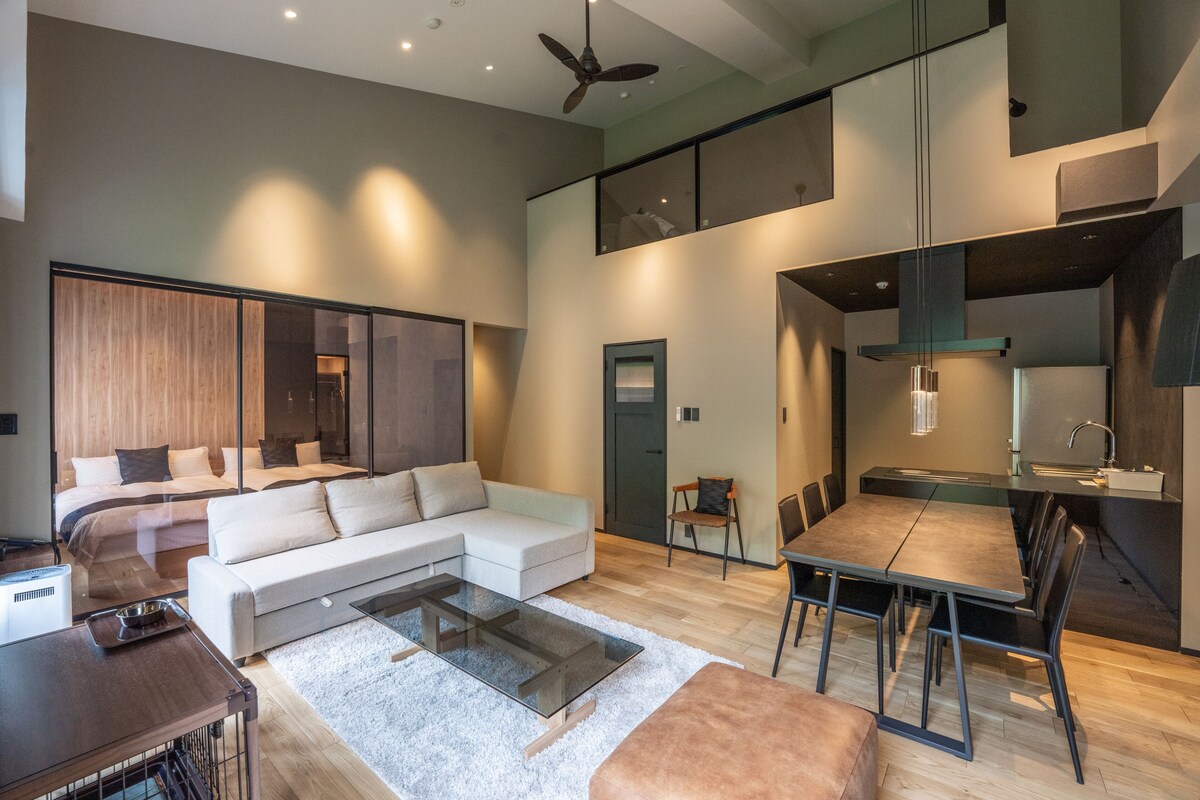 A modern living room with a sofa, a glass coffee table, and a dining area with a table and chairs.