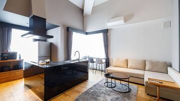 A modern kitchen with a central island, a dining area with a table and chairs, and a living room with a sofa and a coffee table.