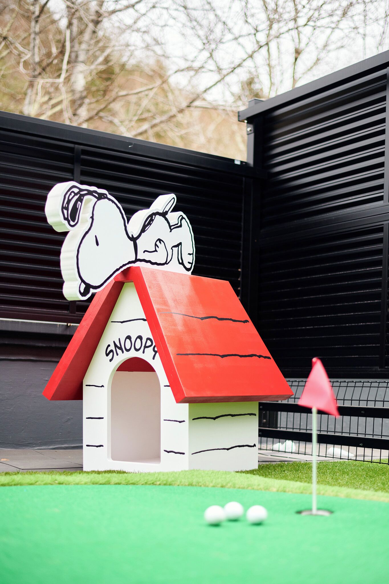 A miniature golf hole with a red-roofed house labeled 'Snoopy' and a red flag.