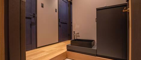 A modern bathroom with a wooden vanity, a dark cabinet, and a sink.