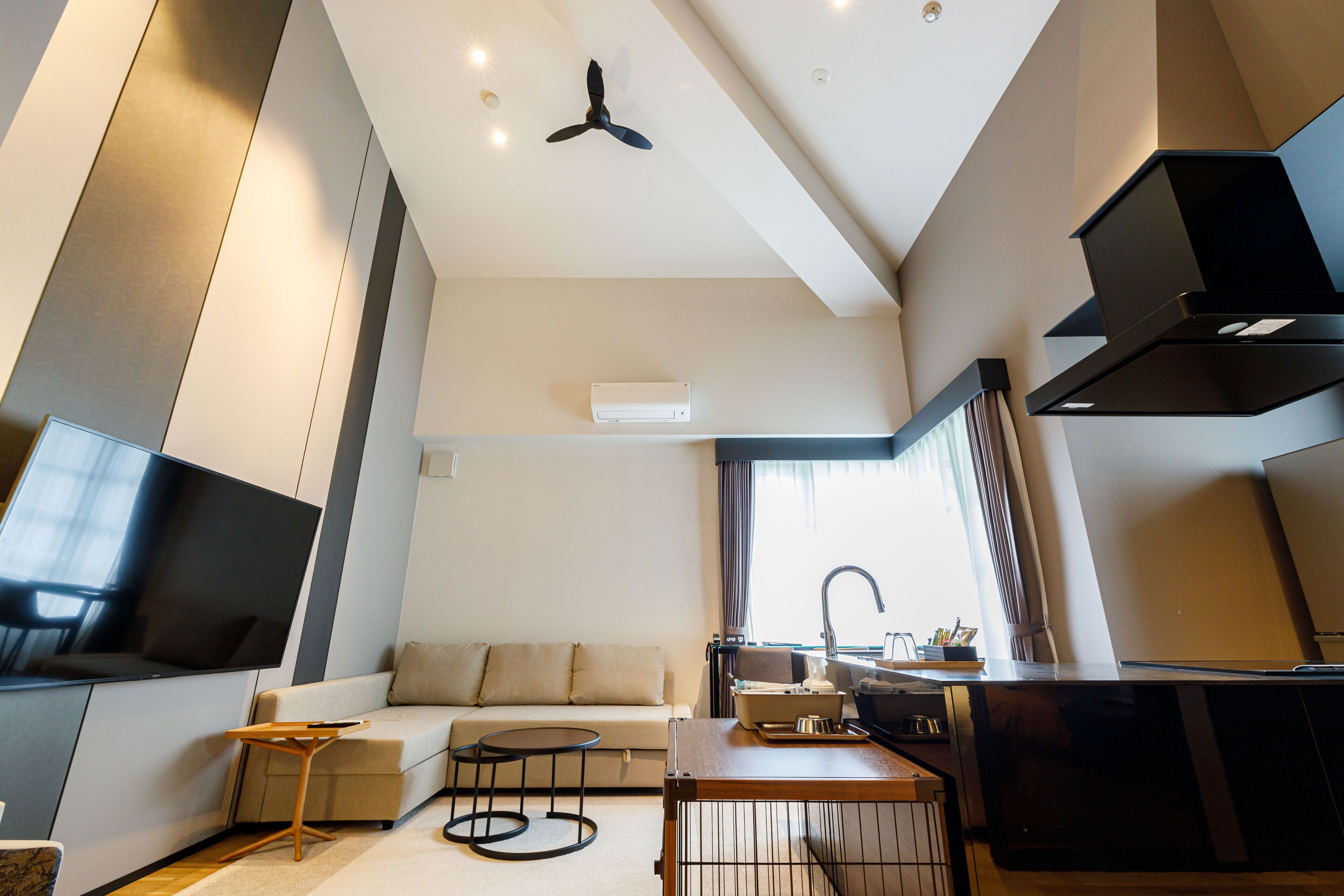 Una sala moderna con televisión de pantalla plana, un sofá, una mesa de centro y una zona de cocina con fregadero y estufa.