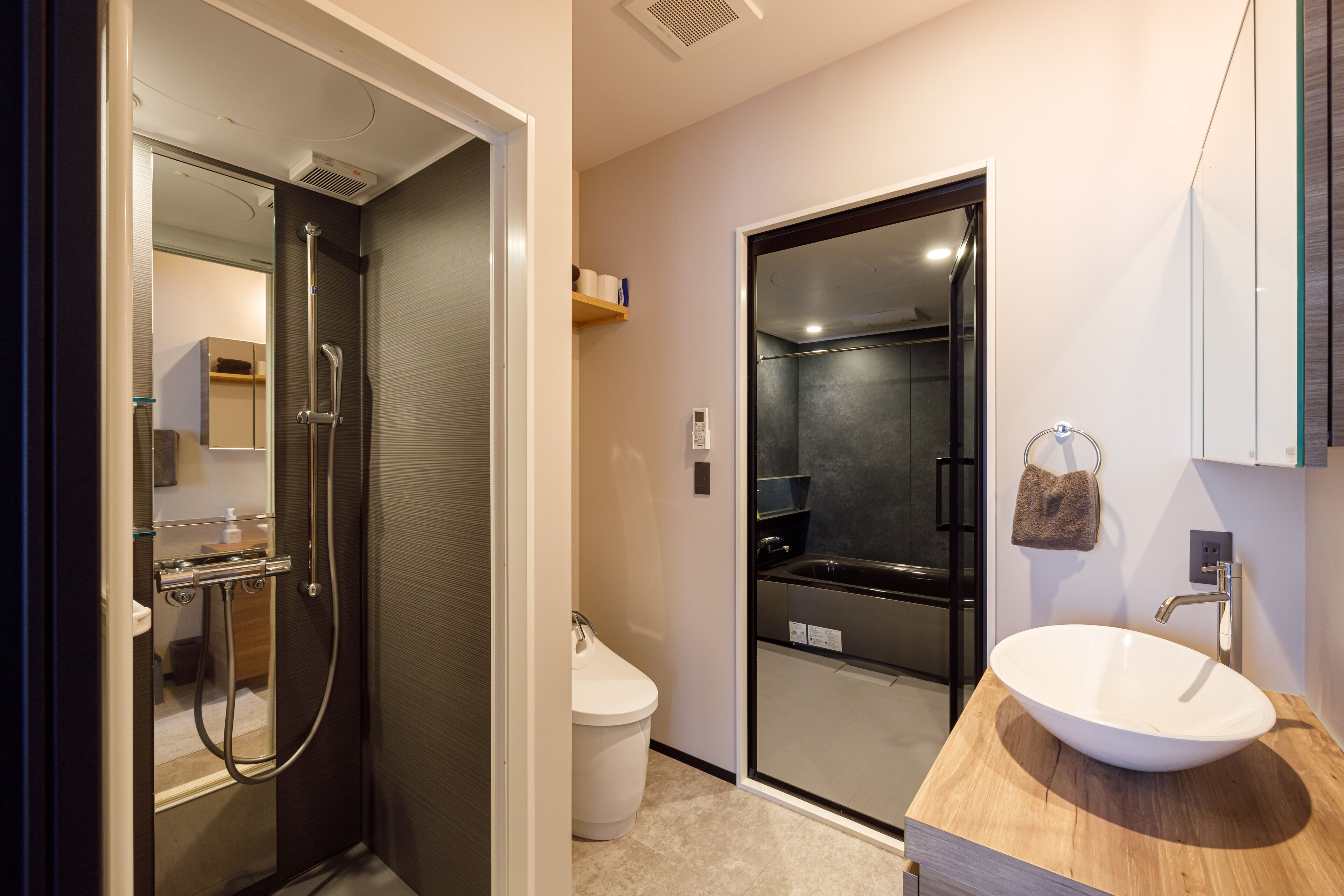 A modern bathroom with a glass-enclosed shower, a white sink, and a wooden vanity.