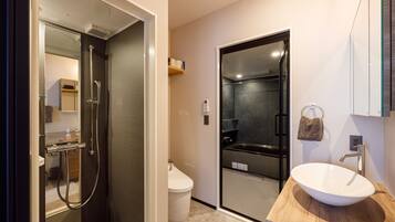 Un bany modern amb dutxa envidriada, un lavabo blanc i un moble de tocador de fusta.
