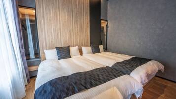 A double bed with white and dark gray linens, a wooden headboard, and a gray wall.