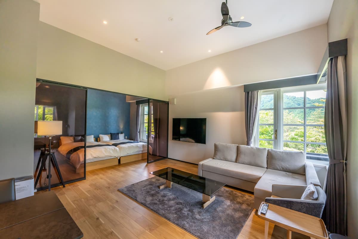Une chambre d’hôtel moderne équipée d’un lit, d’un canapé, d’une télévision et de grandes fenêtres.