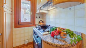 A kitchen with a stove, a window, and a countertop with vegetables. - Casa Gioiosa, Ledro, Italy (Ledro)
