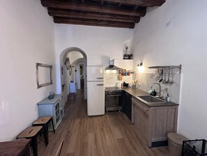 A compact kitchen with a central island, wooden flooring, and a rustic ceiling.