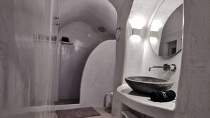 Un baño moderno con un lavabo curvo, un espejo y una zona de ducha.